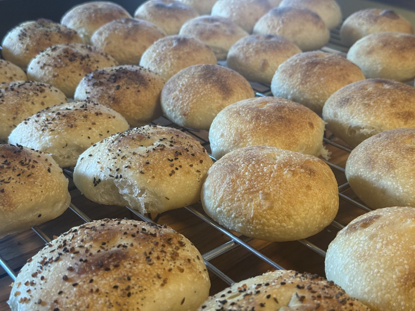 A finished batch of bialys and nahlys cooling on a rack
